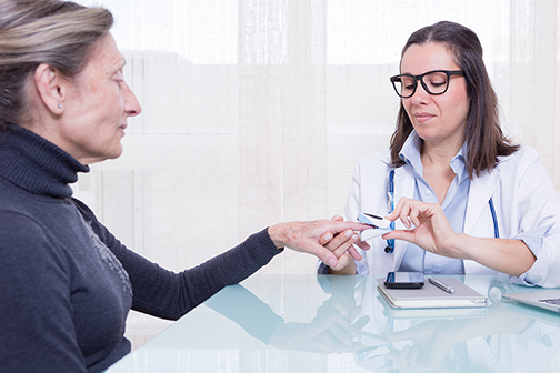 Doctor showing old patient usage of finger pulse oximeter